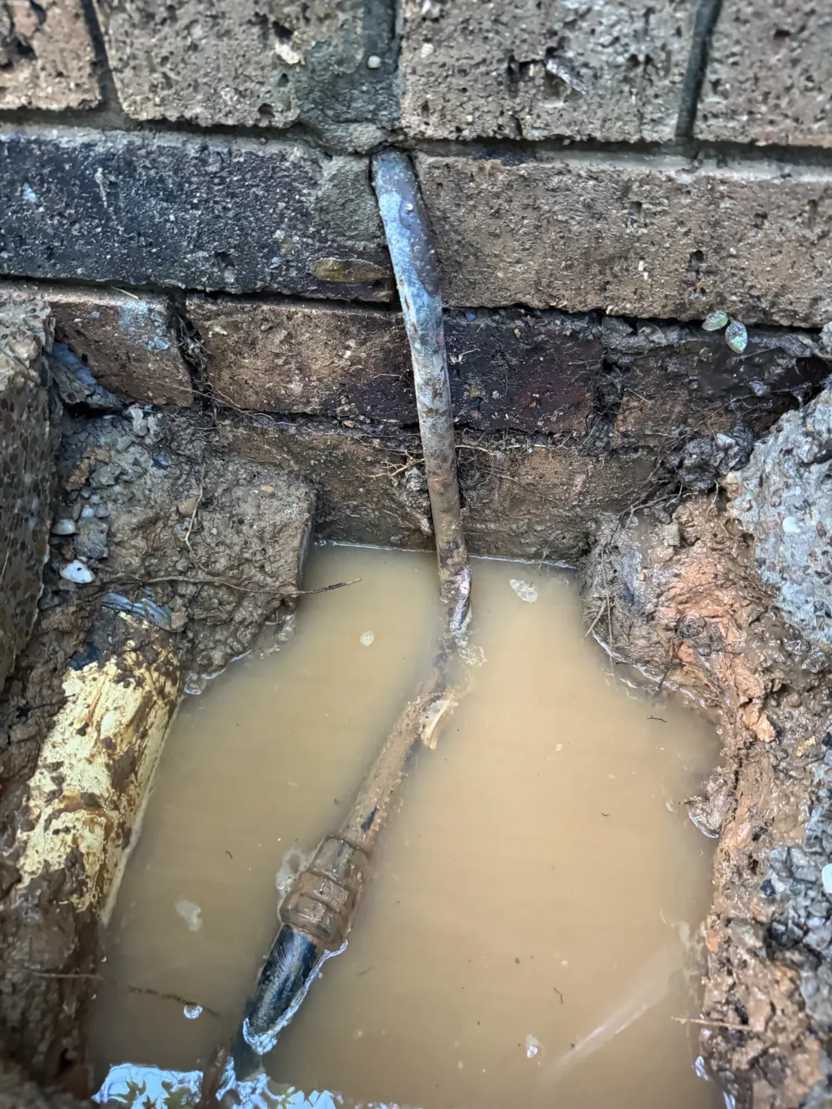 Exposed underground water pipe in a flooded excavation during a burst pipe repair on the Gold Coast